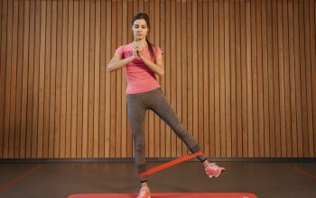 A woman performs leg exercises with a resistance band at a gym, promoting fitness and healthy living.